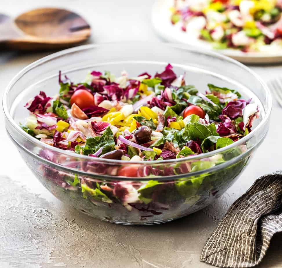 Looking for summer salad recipes? Try this Italian Chopped Salad with Salami & Pepperoncini Peppers! Made of chopped vegetables, herbs, and spices, fresh iceberg lettuce, radicchio, romaine heart, pepperoncini, mozzarella balls, black olives, sugar plum tomatoes, red onion, hard salami, Italian salami, and a homemade Italian Vinaigrette.