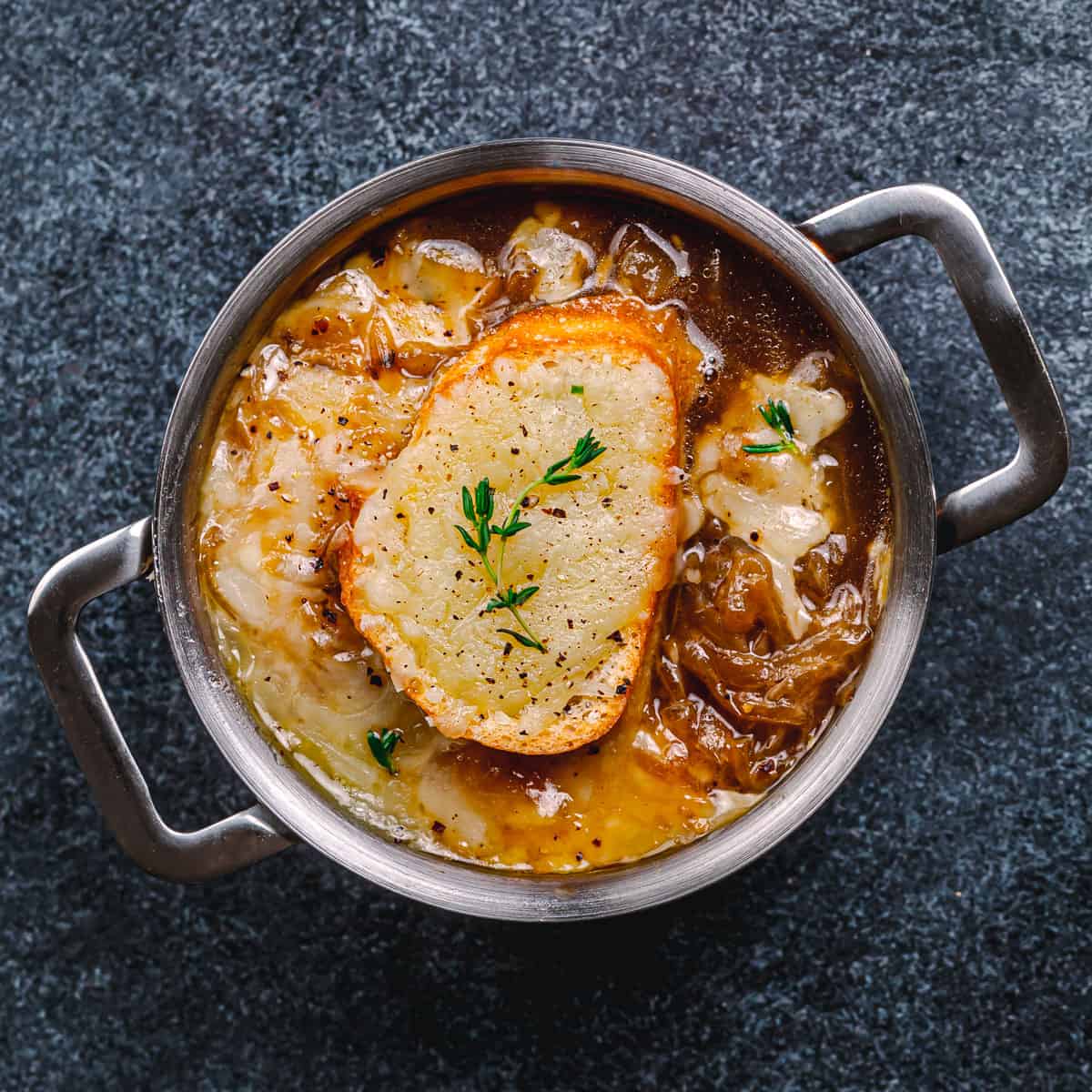 A bowl of classic French onion soup with melted gruyere cheese and crusty bread