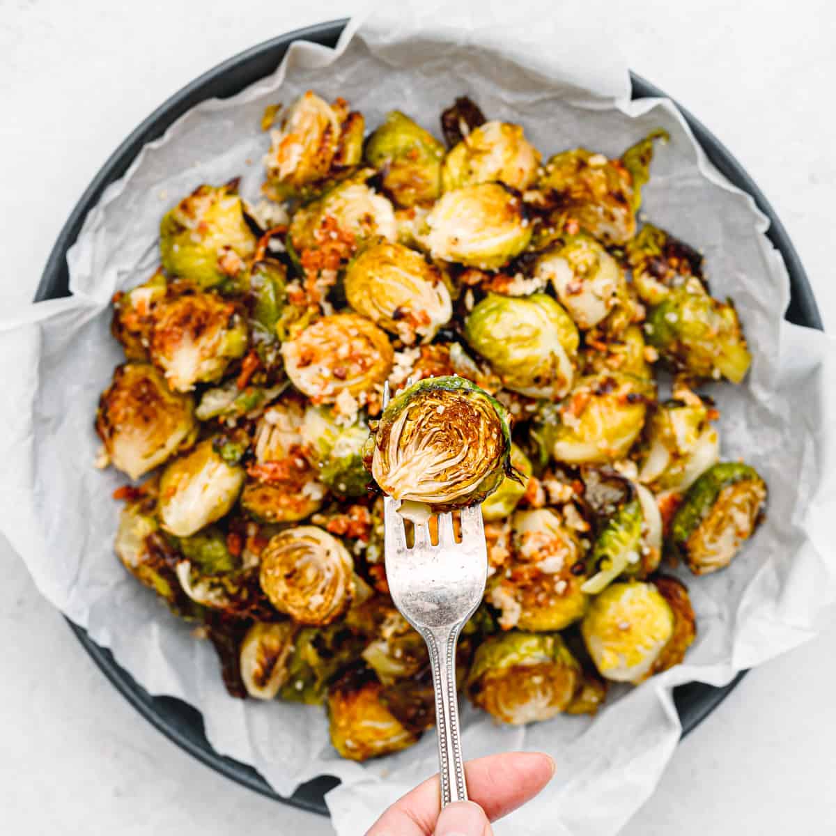 A hand holding a spoon and showing how crispy the brussels sprouts are