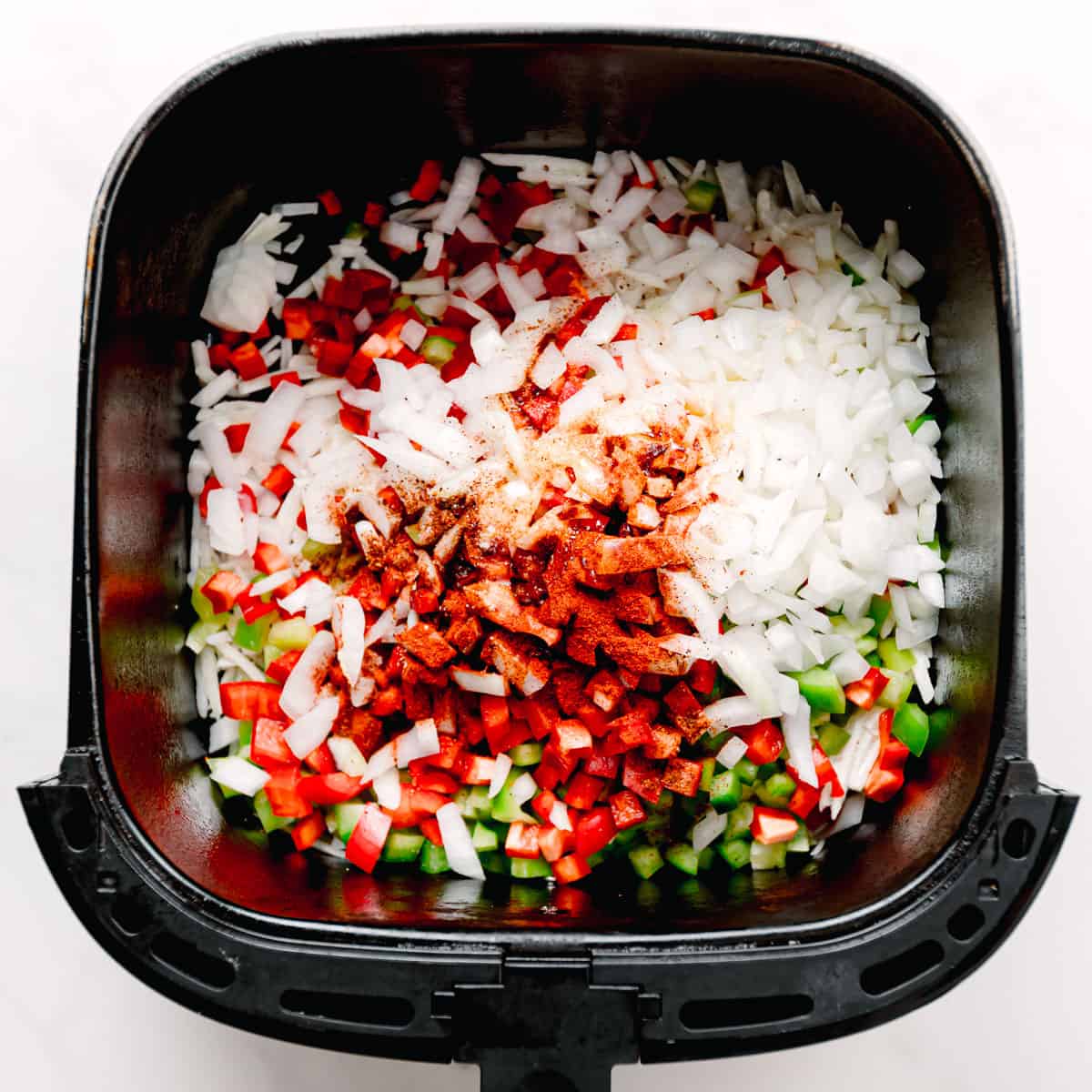 Place the frozen shredded hashbrowns, diced bell peppers, onion, paprika, garlic powder, salt, and black pepper in the air fryer basket.