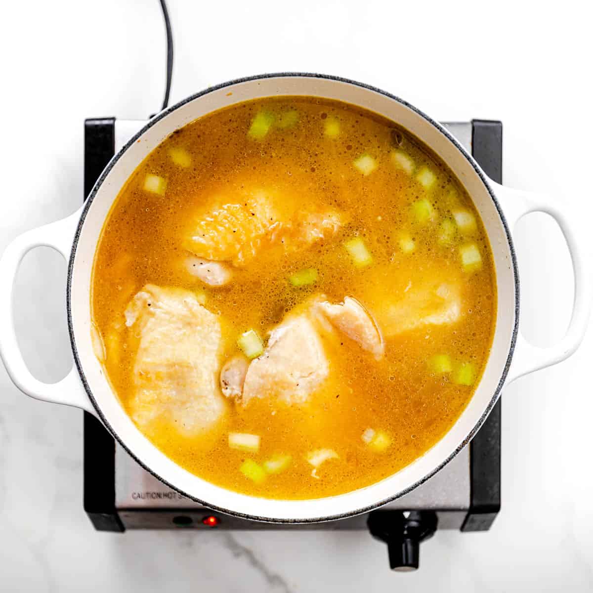 Add a small amount of broth, stirring to loosen browned bits from pan. Add carrots, celery, bay leaf, poultry seasoning, and the remaining broth. Increase the heat and bring the broth to a boil, then lower the heat to medium, simmer, covered, until the chicken is fully cooked for 20-25 minutes.