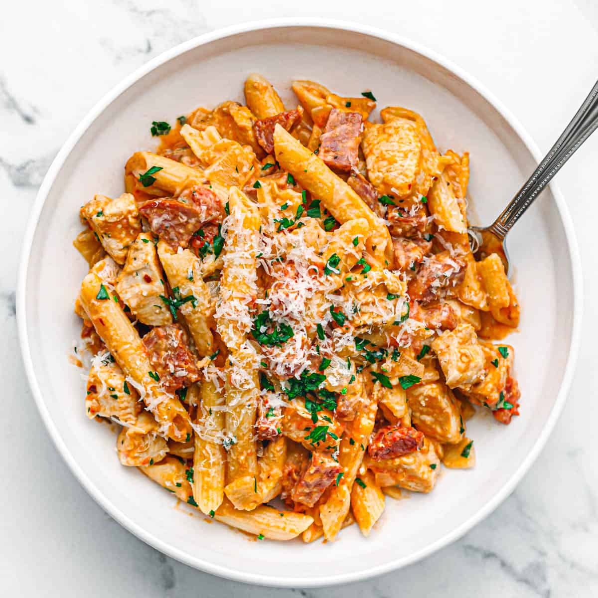 chicken and chorizo pasta on a white plate.