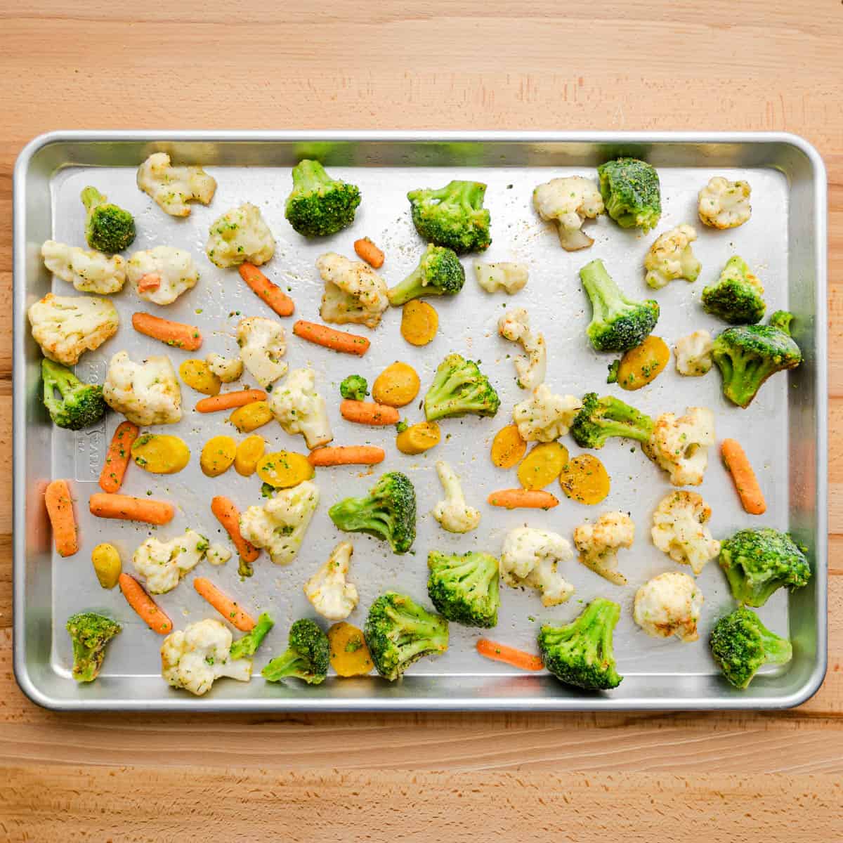 Remove the hot pan from the oven and carefully put the seasoned frozen vegetables onto the sheet pan, in a single layer. 