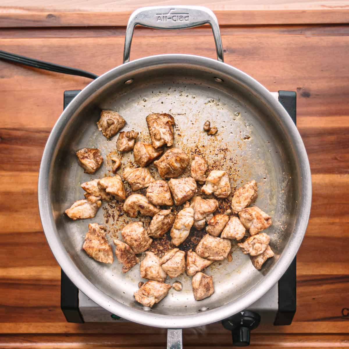 Place the chicken cubes in the skillet and brown them until they are almost cooked.