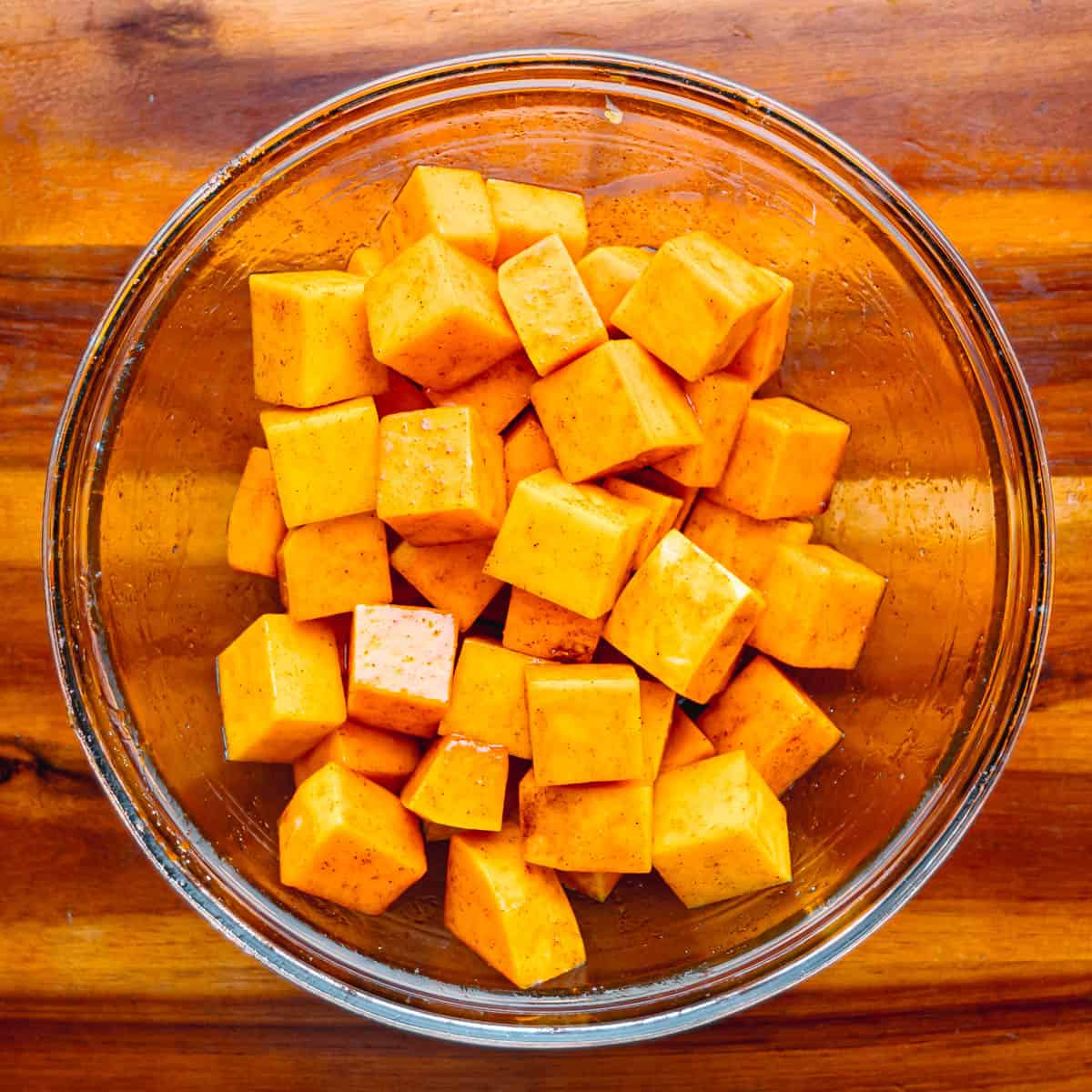 Pour the seasoning mixture over the butternut squash cubes and gently massage it to ensure even coating.