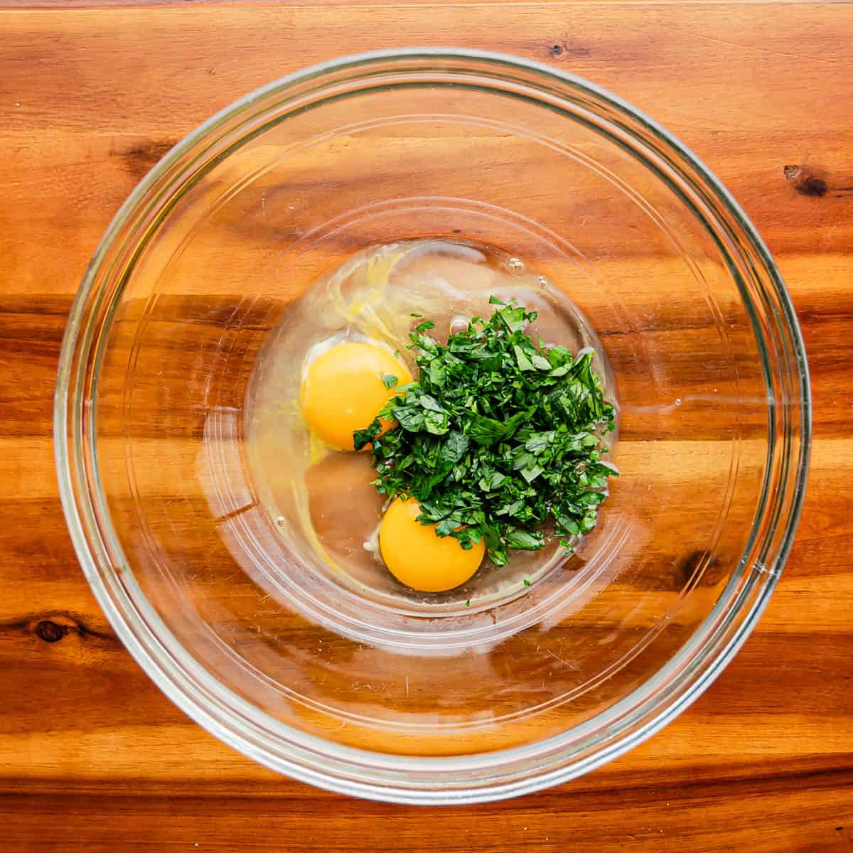 In a large baking dish or mixing bowl, beat eggs and incorporate parsley.