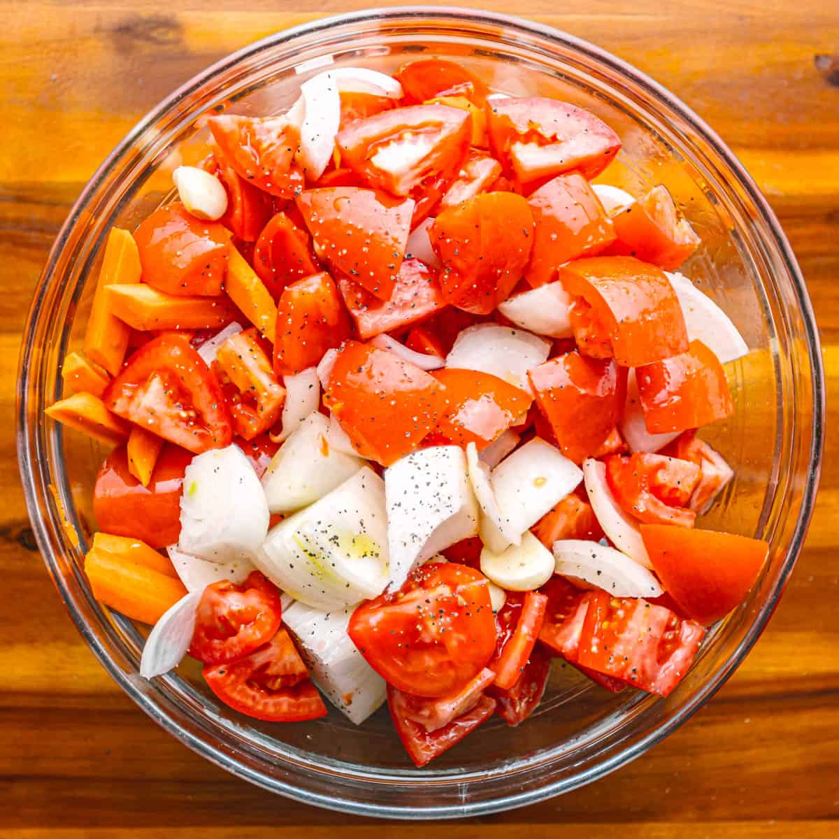 Toss garlic, tomatoes, onion, and carrot in olive oil, salt, and black pepper.