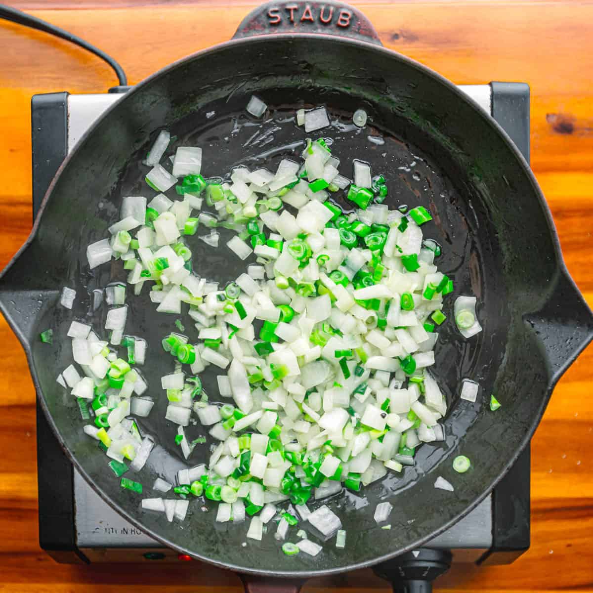 Heat oil in a large skillet. Sauté onion and scallions for 3-4 minutes until softened over medium heat. Season with salt and black pepper.