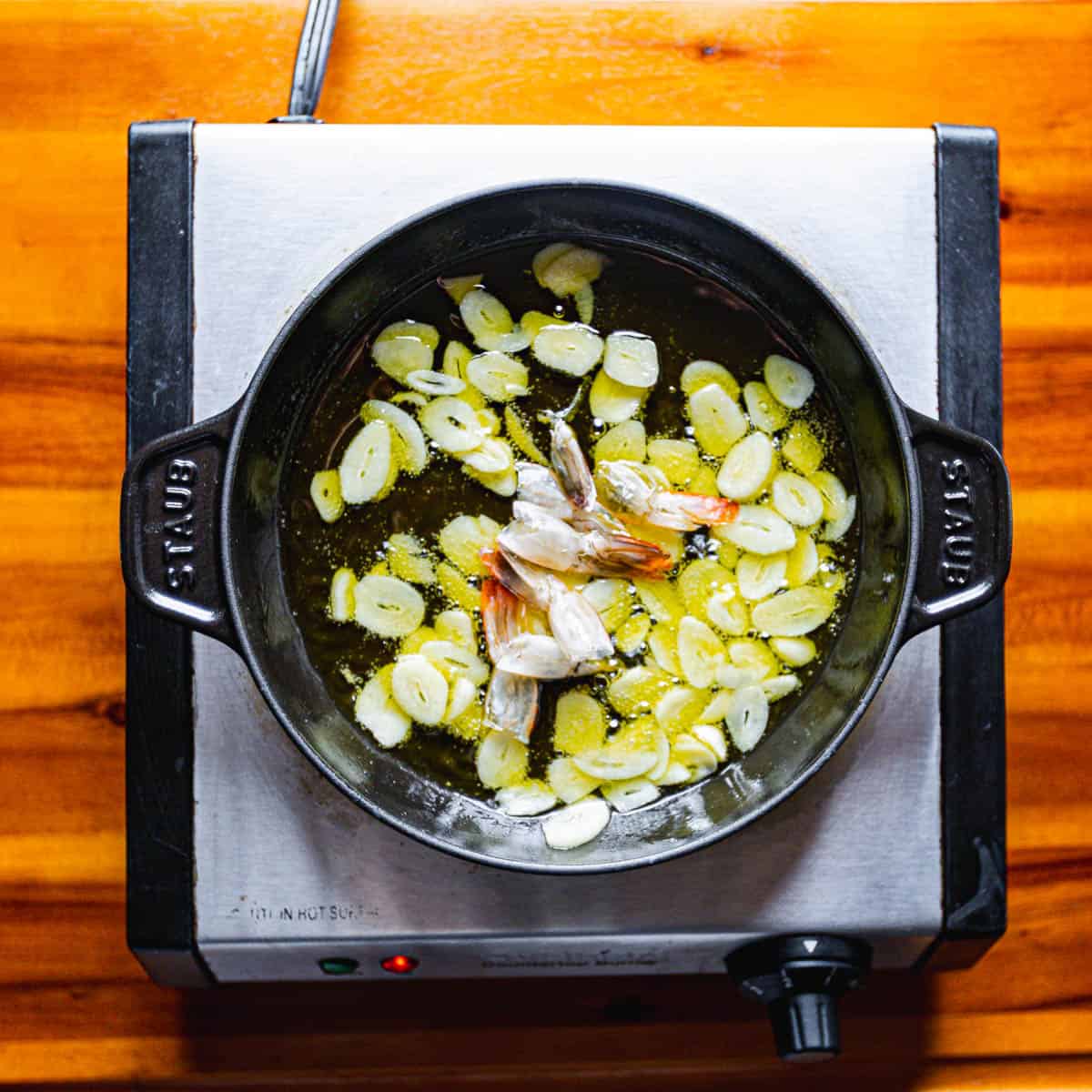 In a pan, combine olive oil and sliced garlic. Slowly cook the garlic over low heat until it becomes fragrant and just starts to brown. 