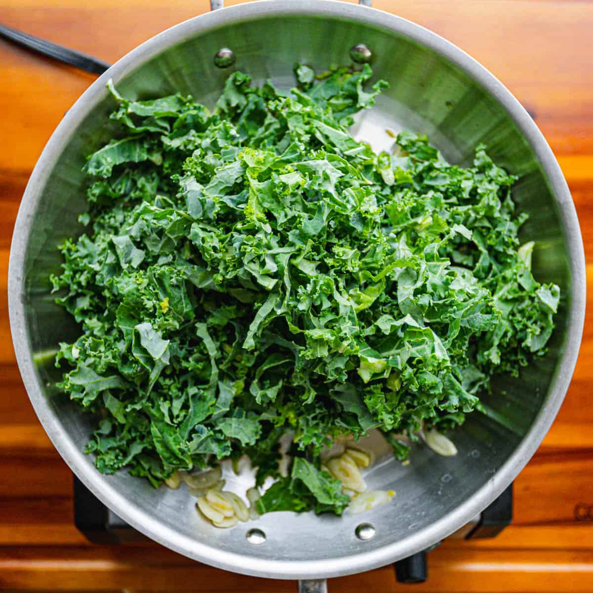 Gradually add kale to the pan, working in batches, and drizzle a bit of broth each time.