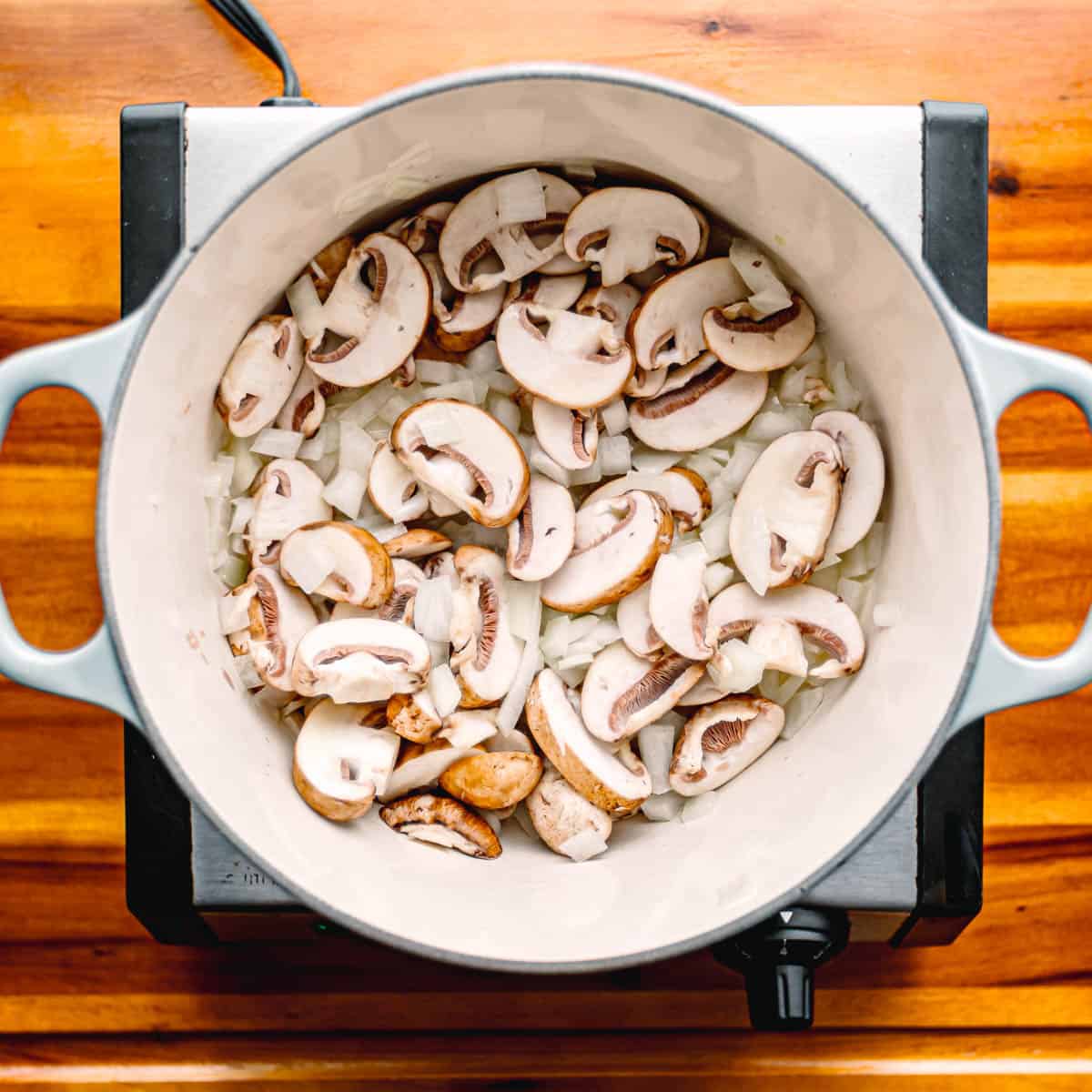 Melt butter in a saucepan over medium-high heat. Toss in the onions and mushrooms, and cook until they soften, around 5 minutes.