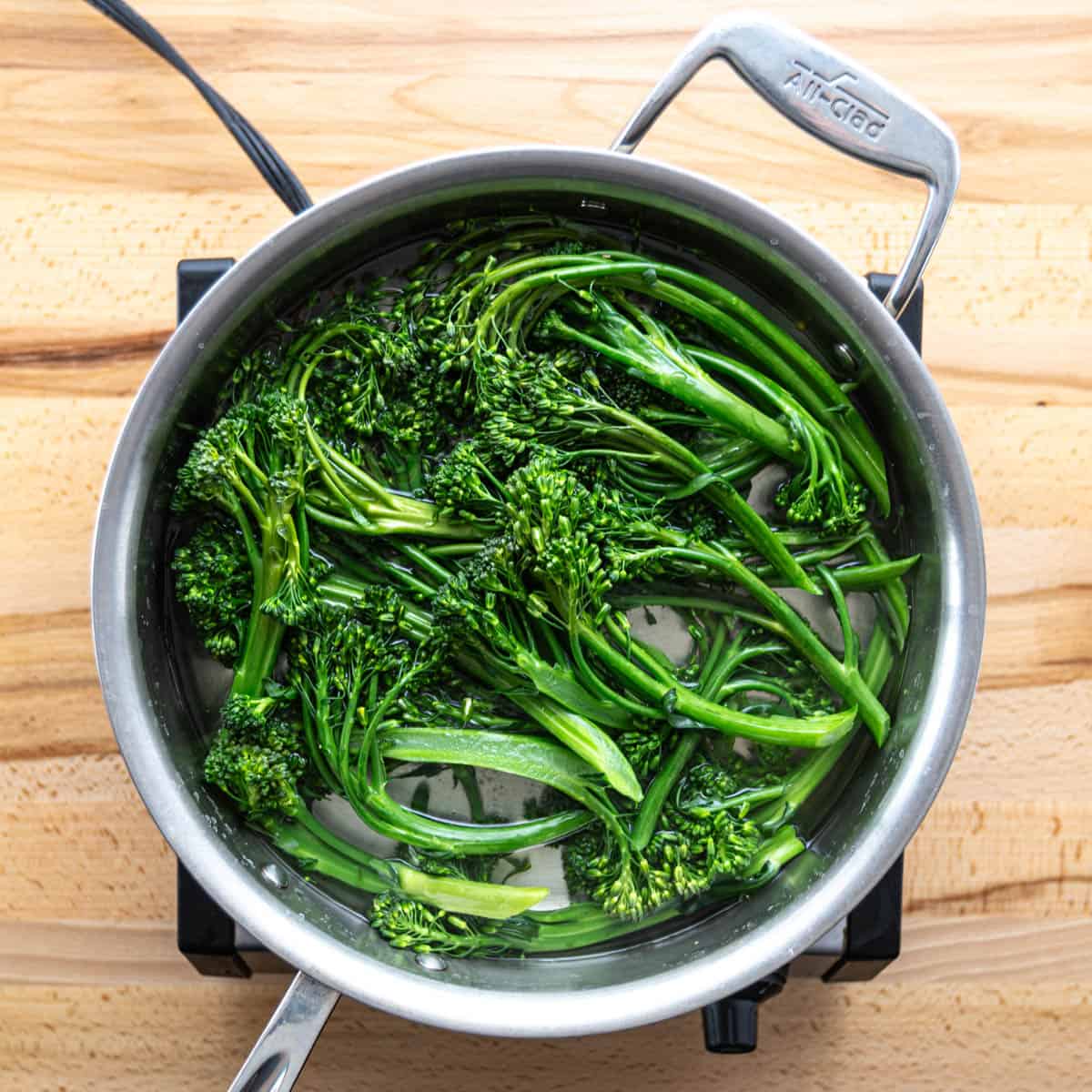 Boil some water in a pot with a pinch of salt. Cook the broccolini in the boiling water for about 2 minutes until they're a bit soft but still have a nice crunch.