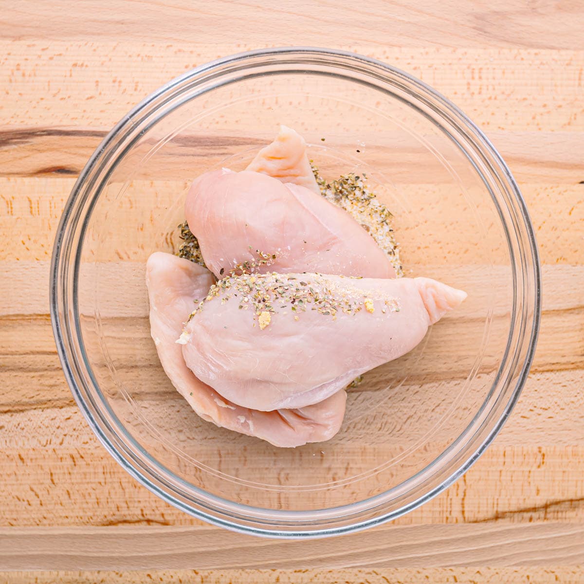 Begin by seasoning the chicken breast with oregano, salt, garlic powder, and black pepper.