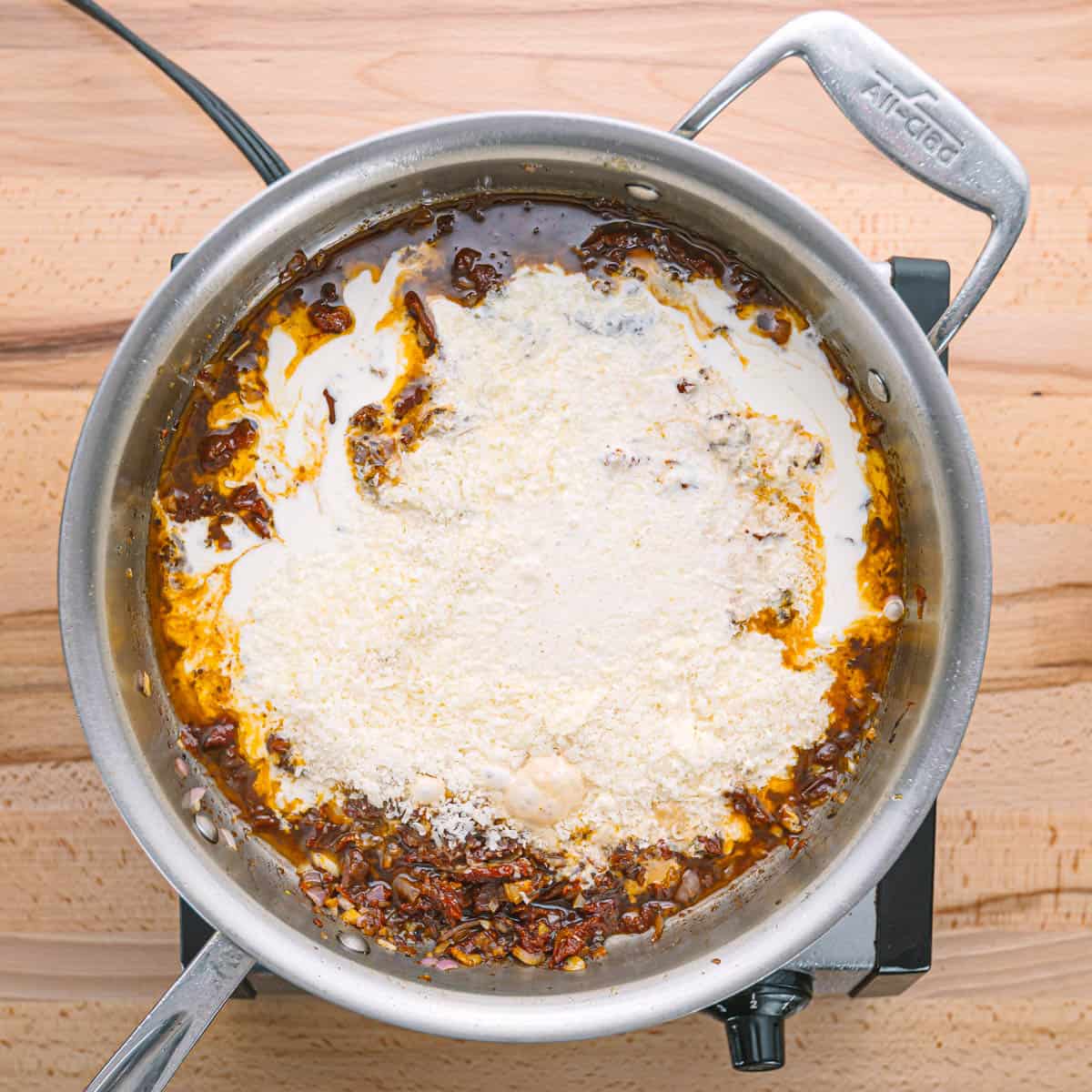 Once the broth is simmering, stir in the heavy cream and grated Parmesan cheese, stirring continuously until the sauce is smooth and creamy. 