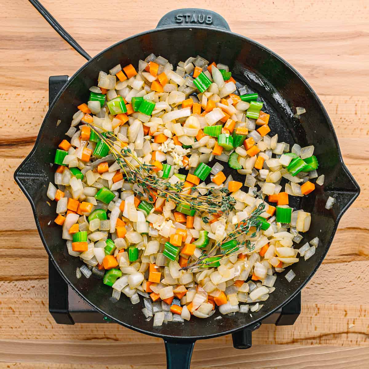 In the same Dutch oven, sauté onion, carrot, and celery until they soften, about 7 minutes. Add garlic and thyme, cooking just until fragrant. Stir in the wine and deglaze the pan, scraping up any browned bits.