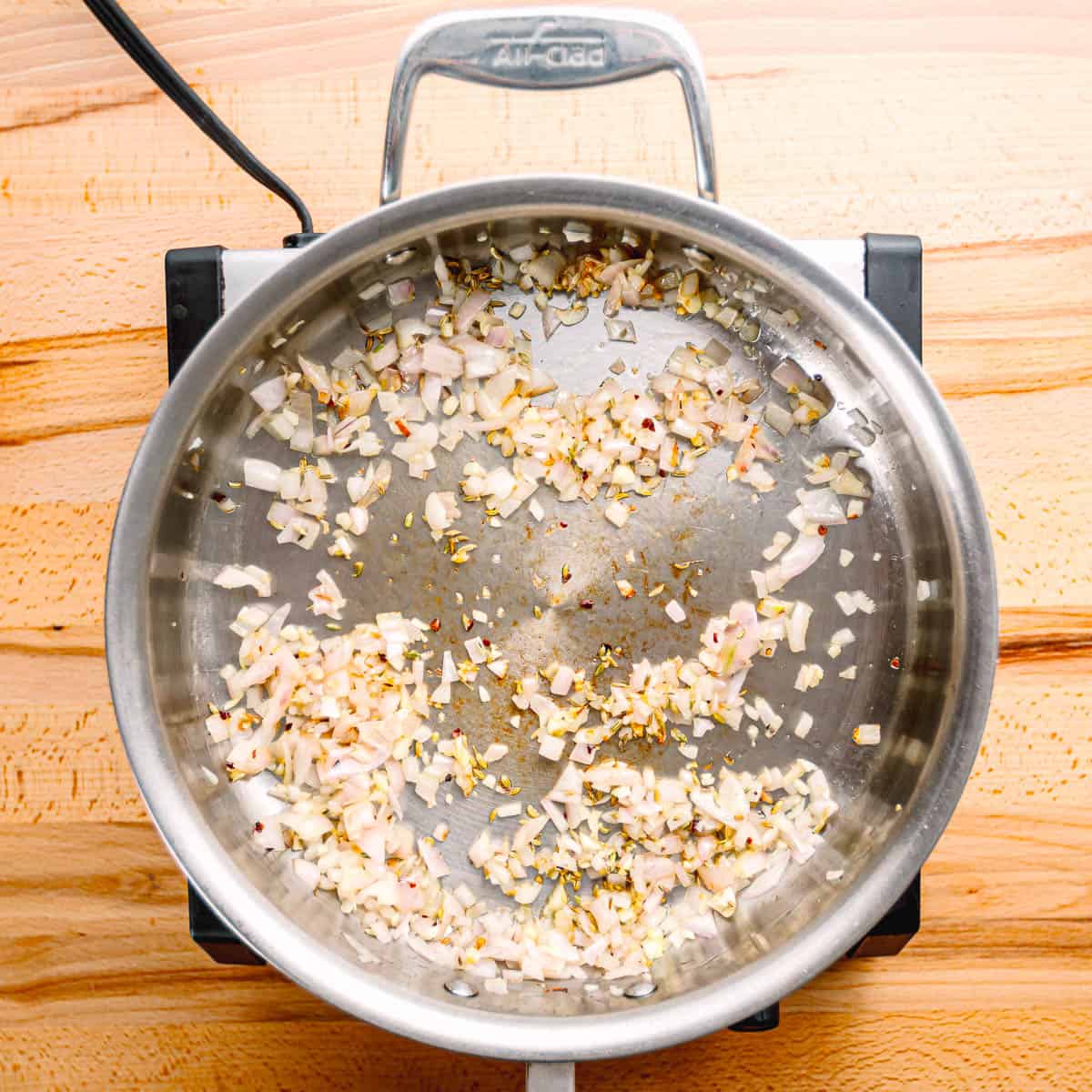 In a pan, heat some olive oil over medium heat. Add chopped shallots, minced garlic, and red pepper flakes (if you like some spice). Cook for 2-3 minutes until the shallots are soft.