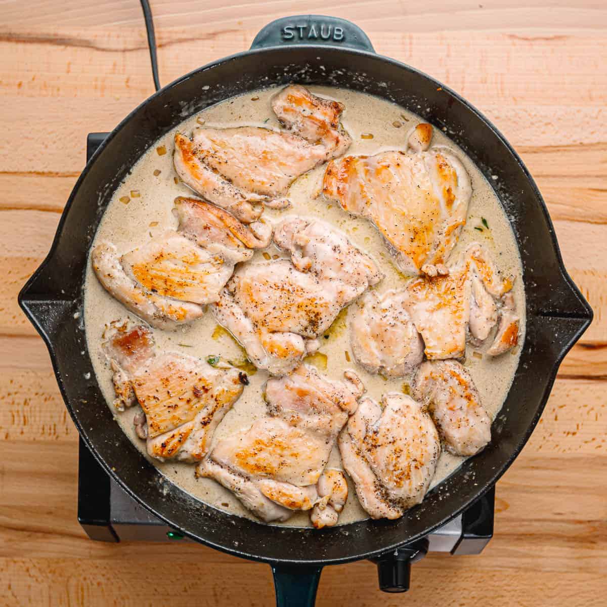 Add heavy cream and simmer, then return the chicken to the skillet and cook until fully done and the sauce thickens.