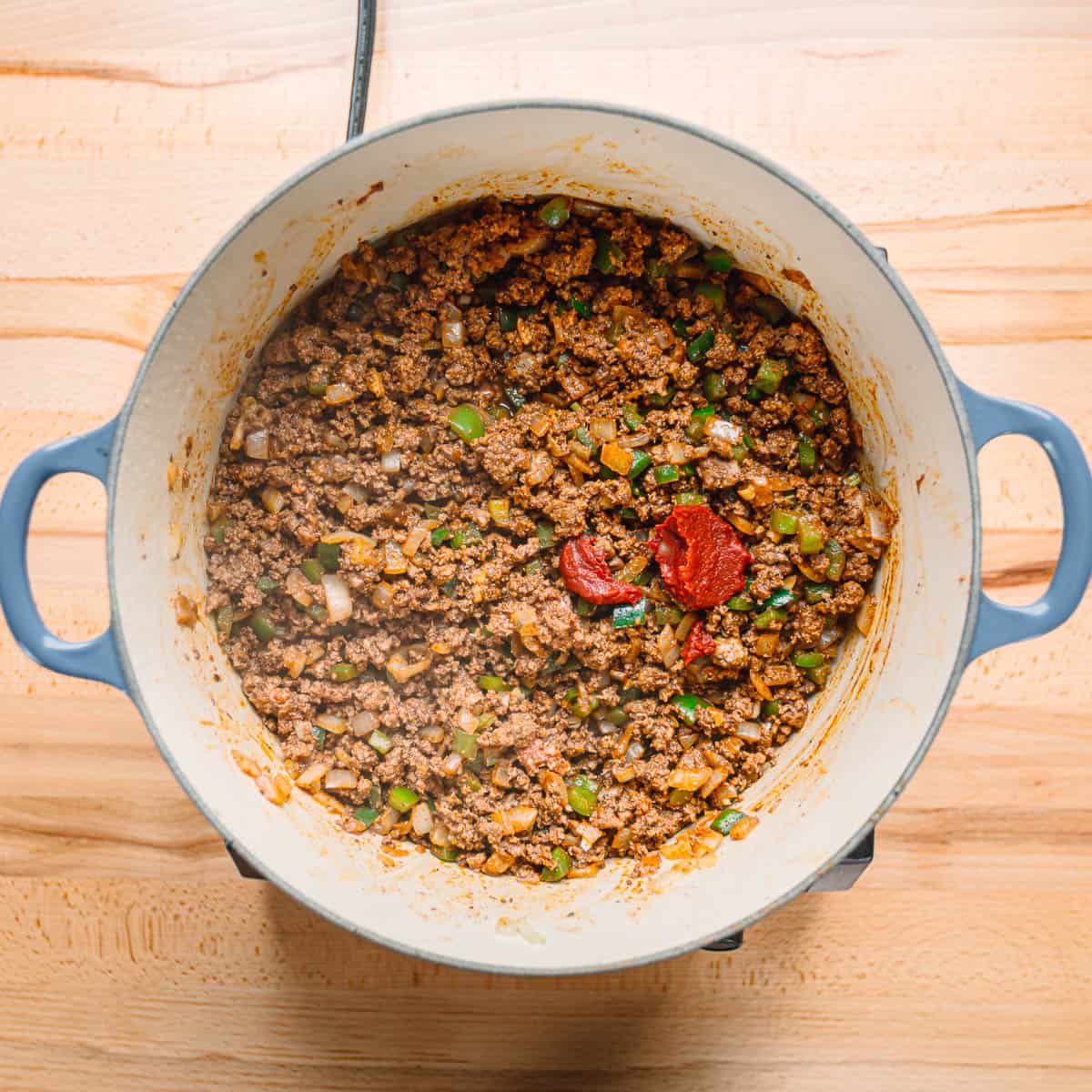 adding tomato paste to ground beef. 