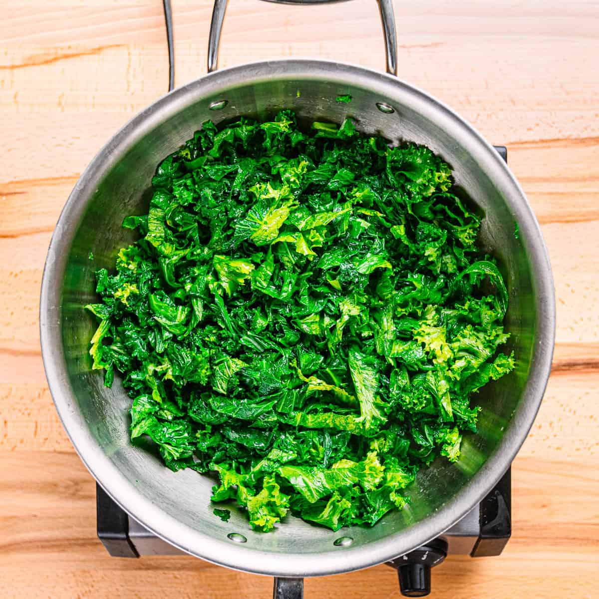 Blanched mustard greens in a stainless steel pot for creamed mustard greens recipe. 