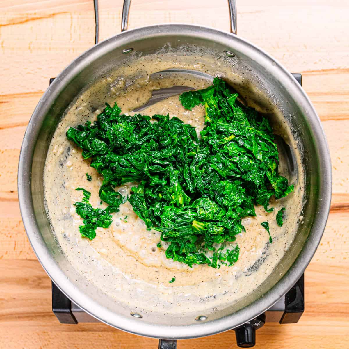 Mustard greens in creamy sauce. It's cooked in a stainless steel pot. 