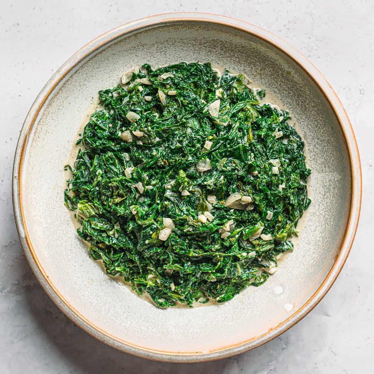 Creamed mustard greens in a bowl with garlic and shallots - rich and savory Southern-style side dish recipe.
