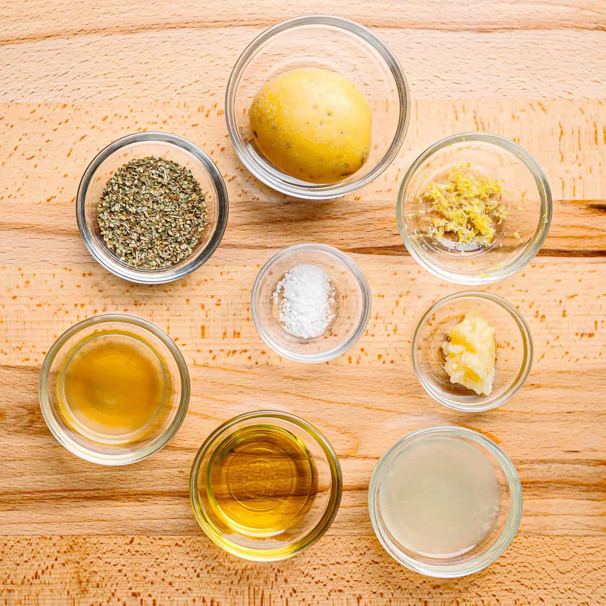 Ingredients for Greek Lemon Potatoes laid out on a countertop potatoes, lemons, olive oil, garlic, oregano, salt, pepper, and chicken broth.