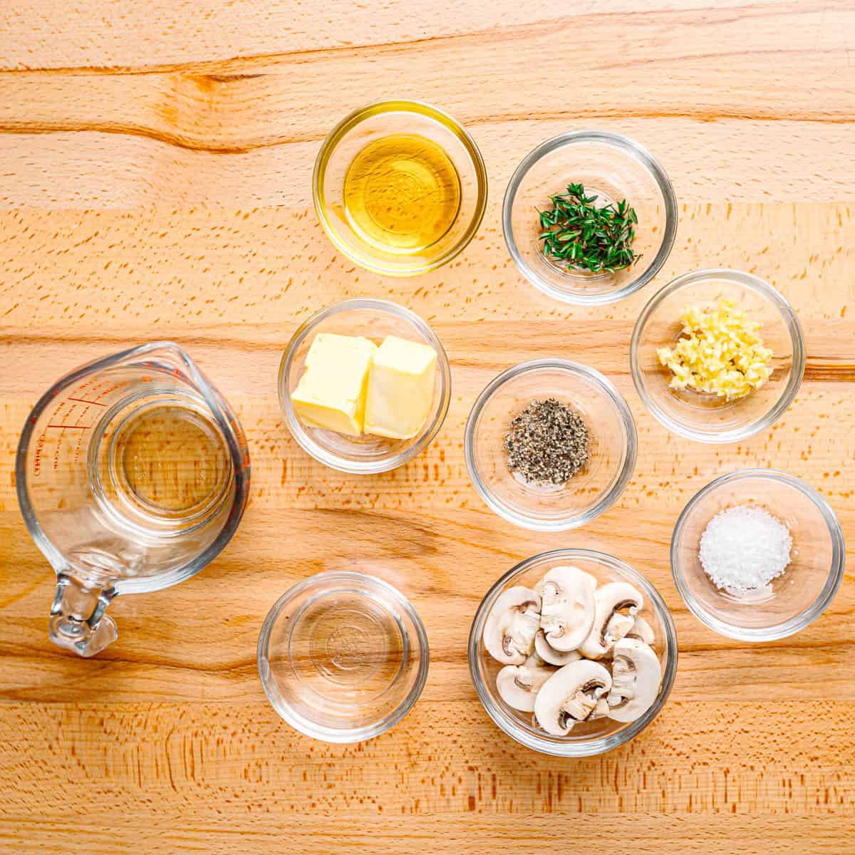 Fresh mushrooms, garlic, olive oil, and herbs on a table.