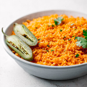 Fluffy red Mexican rice with cilantro and jalapeños in a bowl.