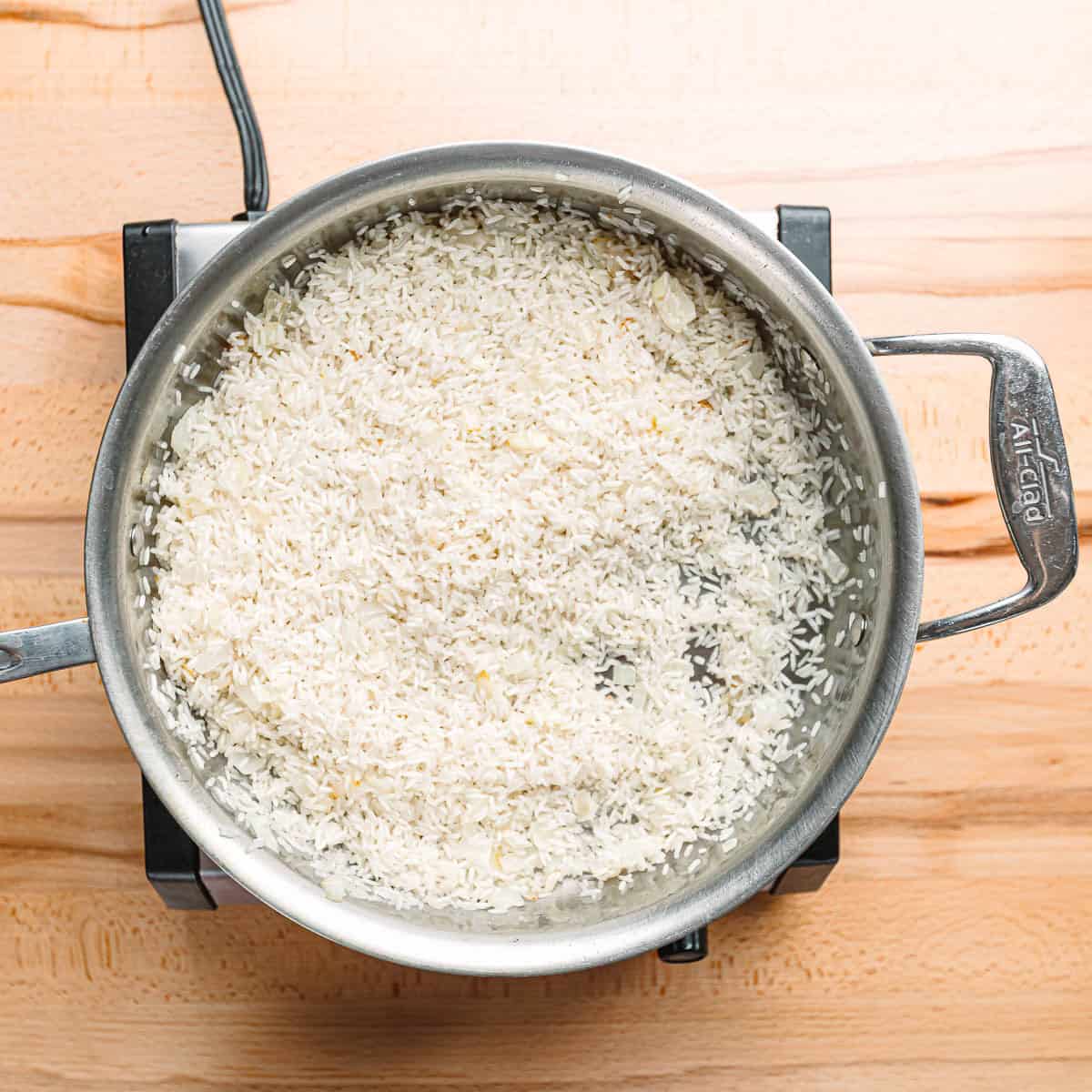 Toasting long-grain rice in hot oil until golden brown.