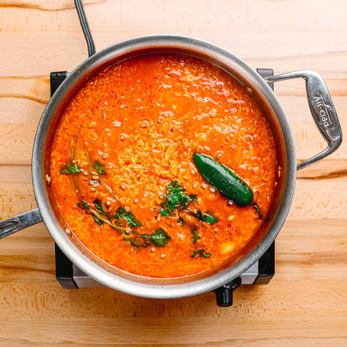 Pouring chicken broth into sauté pan and scraping bottom of the pan.