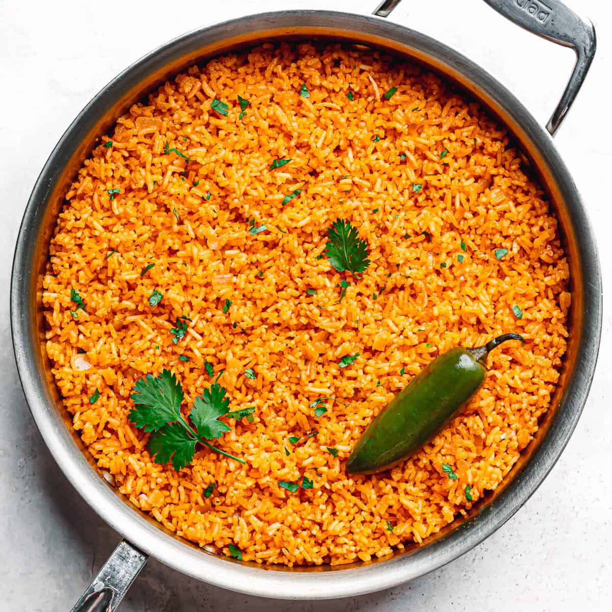Easy one-pot Mexican rice in sauté pan with fresh cilantro and jalapeño on top.