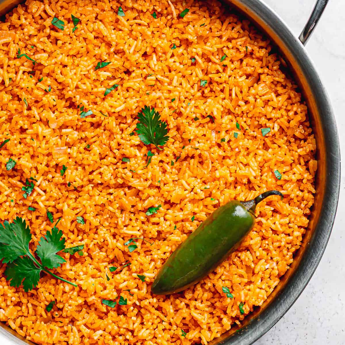 One-pot Mexican rice served in a skillet with green cilantro and jalapeño.