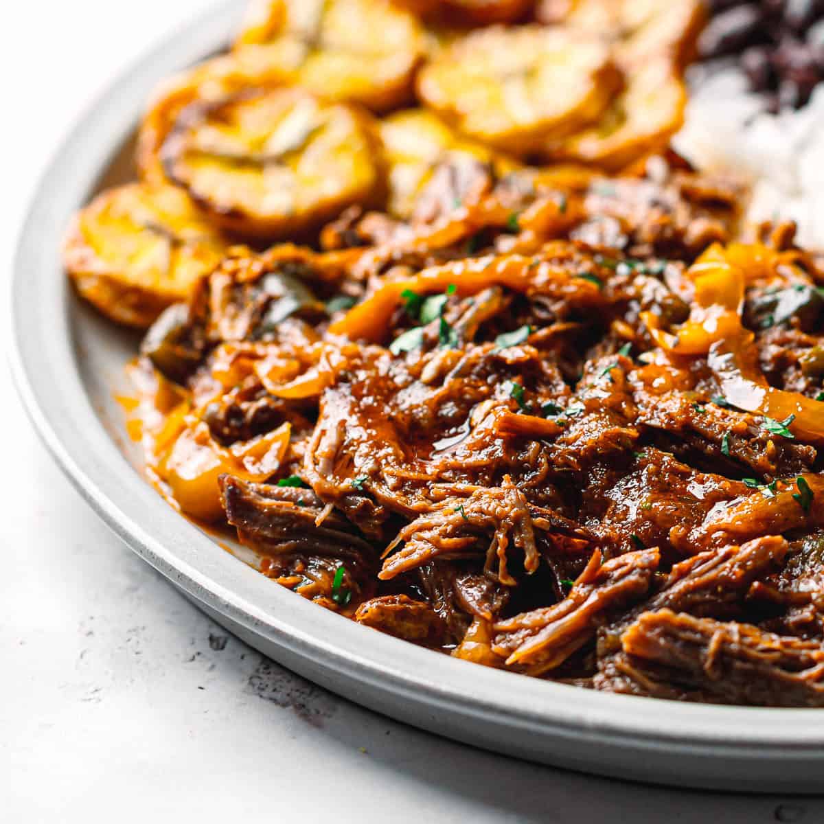 Cuban shredded beef ropa vieja served with rice, black beans, and sweet air-fried plantains.