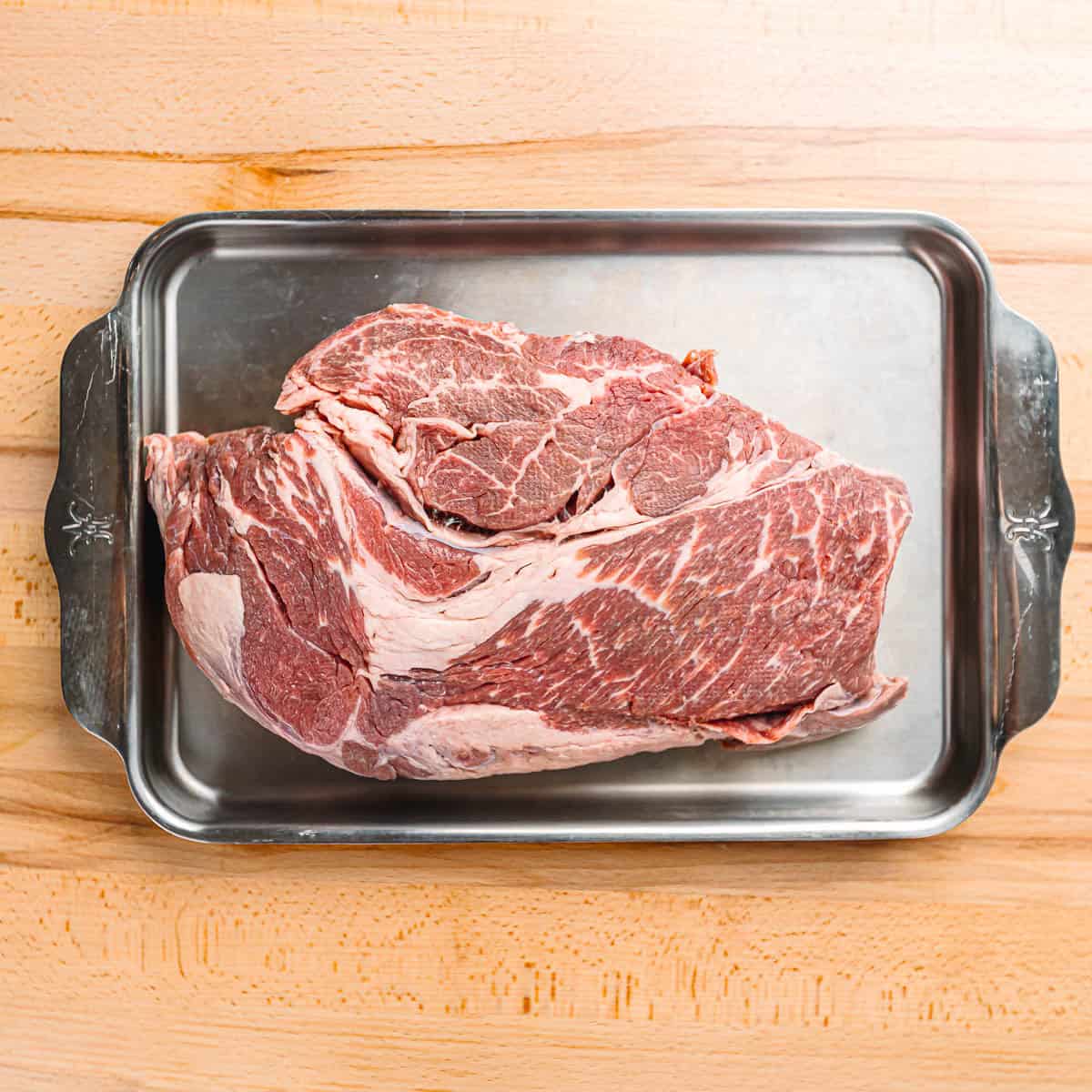 Raw chuck roast on a baking sheet ready to cook for ropa vieja.