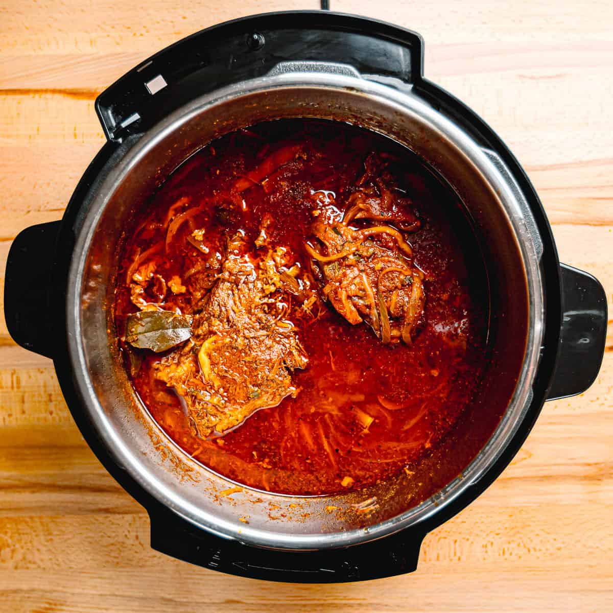 Tender shredded beef mixed with tomato and pepper sauce in a pot.