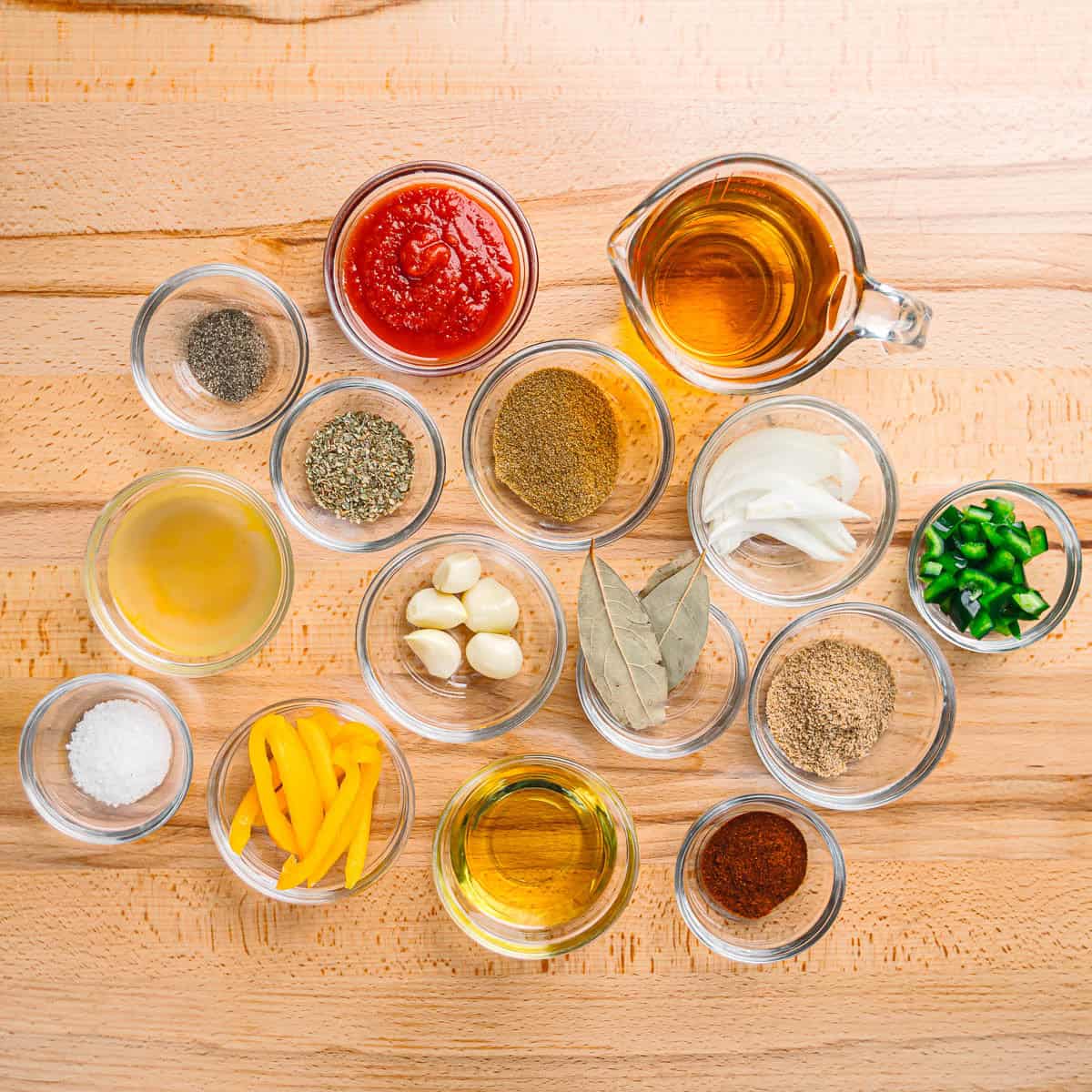 Fresh ingredients for ropa vieja including onions, red bell pepper, poblano pepper, garlic, and spices.