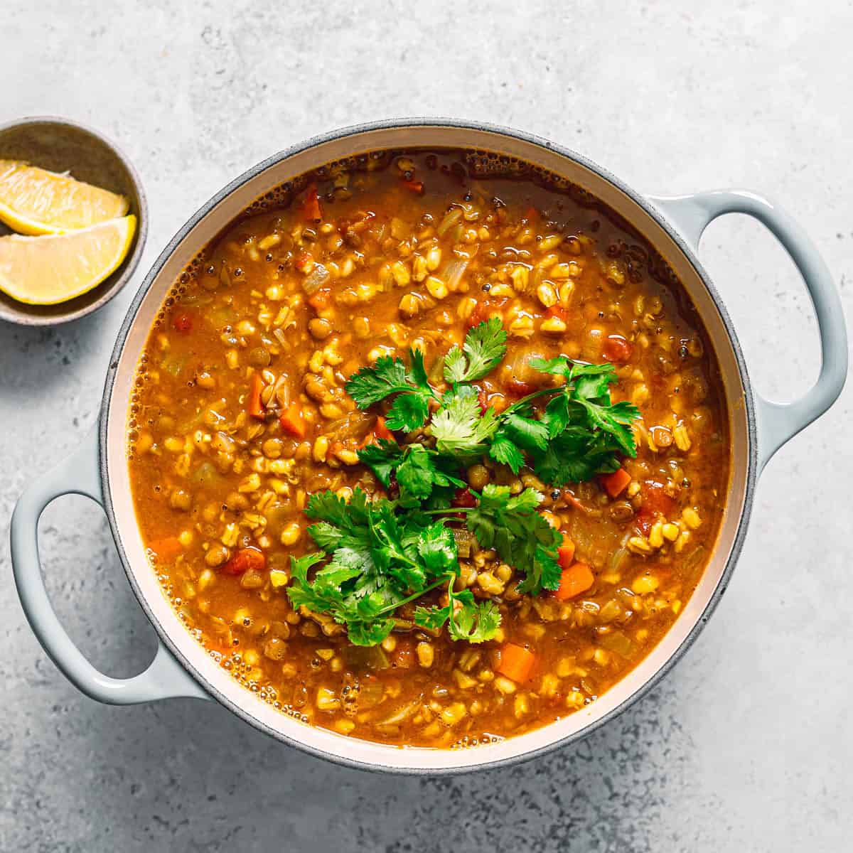 Thick barley lentil soup ready to serve in a blue Dutch oven.