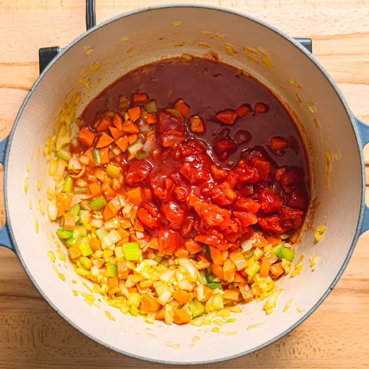 Adding canned tomatoes to deglaze the pan.