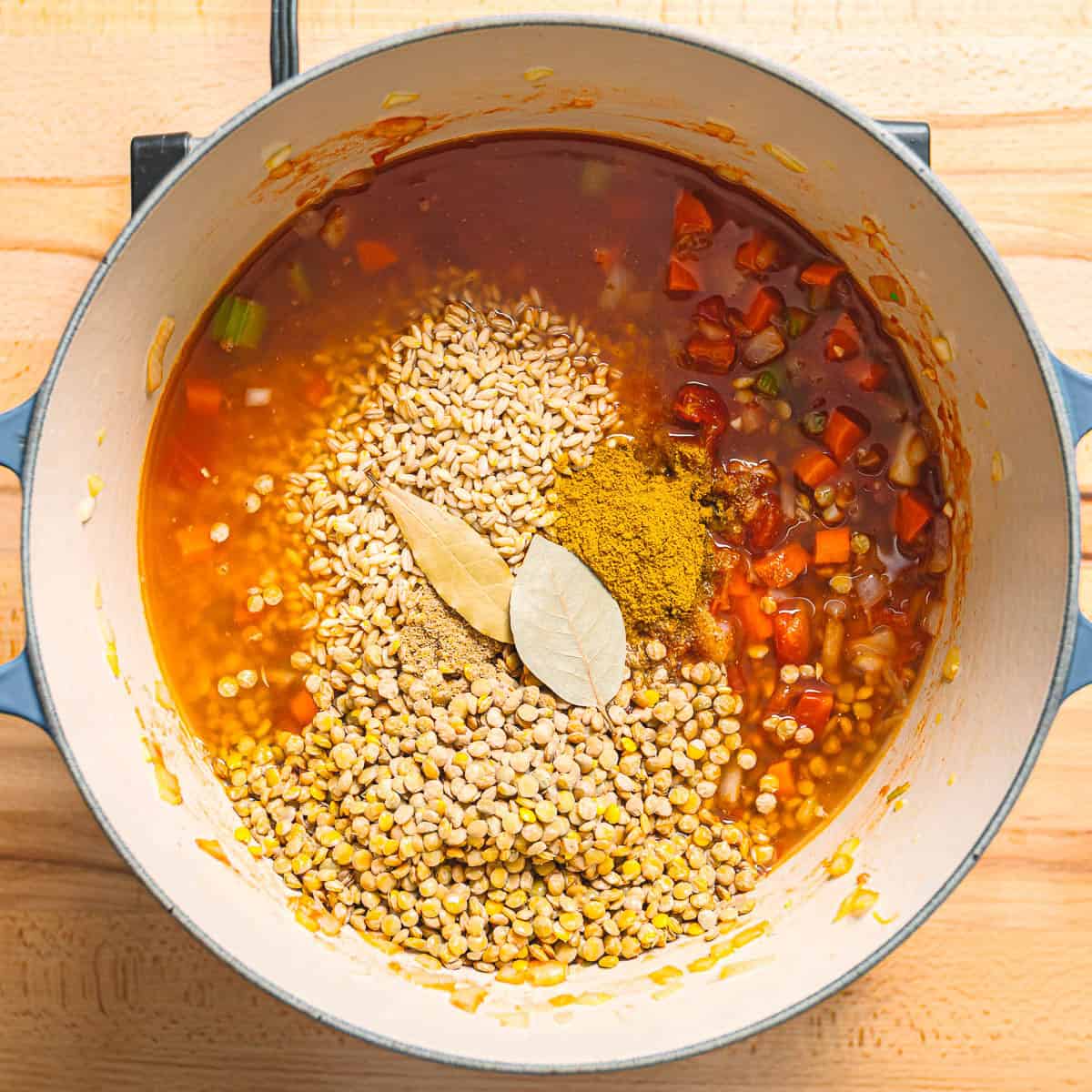Lentils, barley, broth, and spices are added.