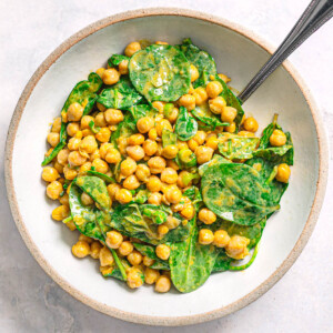 High protein chickpea spinach salad served in a ceramic bowl.