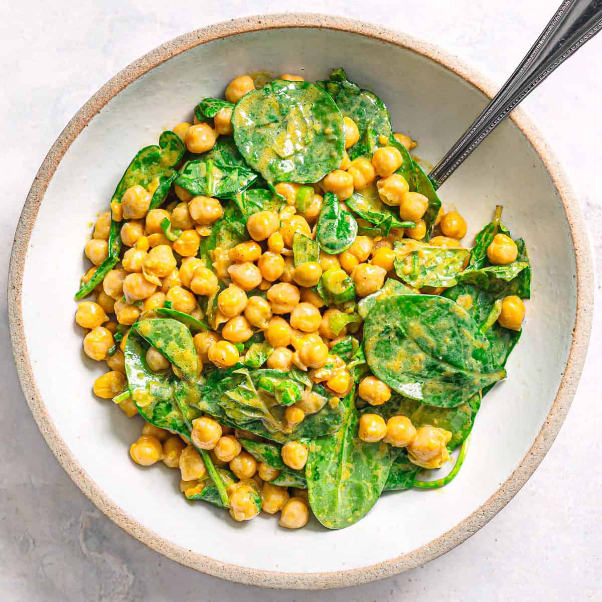 High protein chickpea spinach salad served in a ceramic bowl.