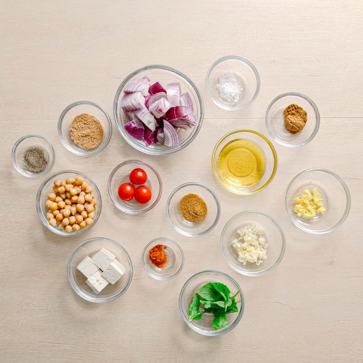 ngredients for masala chickpeas including chickpeas tofu tomatoes and Indian spices on a table.