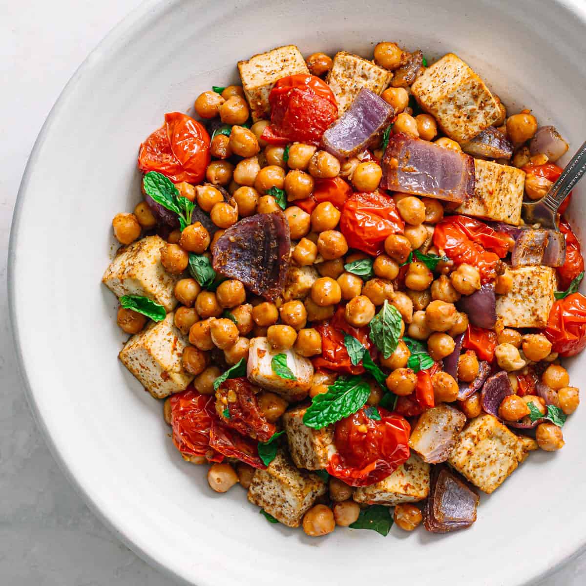 Vegan masala chickpeas with tofu and tomatoes in a white bowl top view.