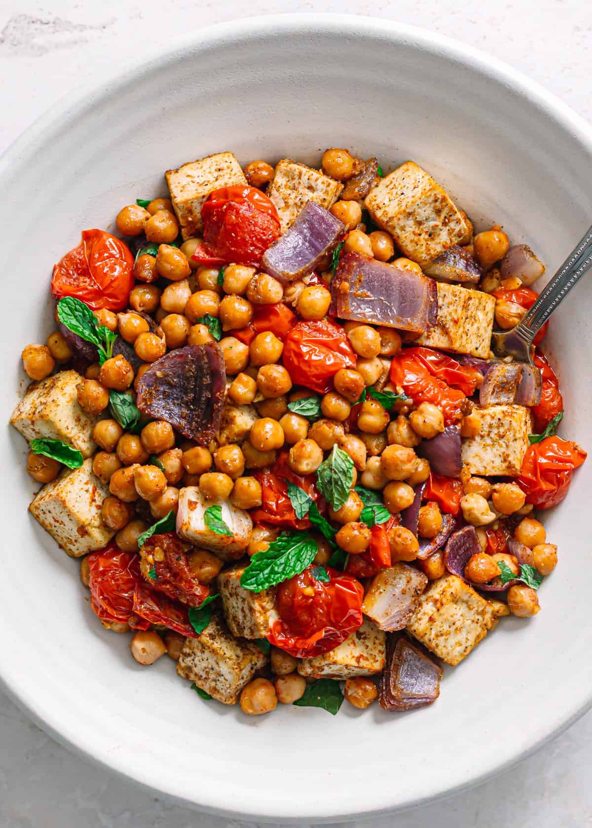 Vegan masala chickpeas with tofu and tomatoes in a white bowl top view.