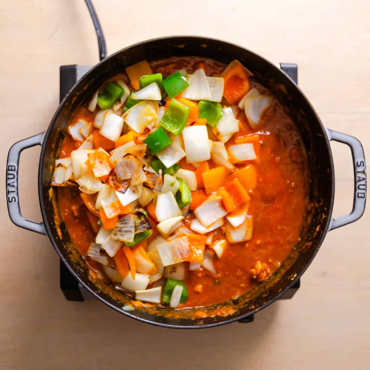 Blistered vegetables added to Chicken Jalfrezi in skillet.