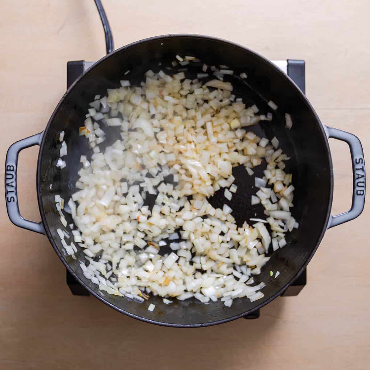 Finely diced onions browning in skillet for Chicken Jalfrezi.