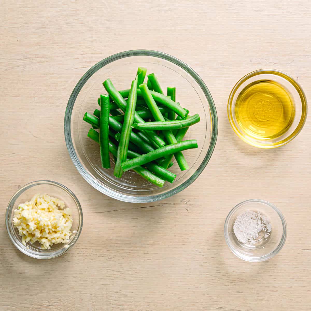 Ingredients for sautéed garlic green beans including fresh green beans, garlic, olive oil, and salt.
