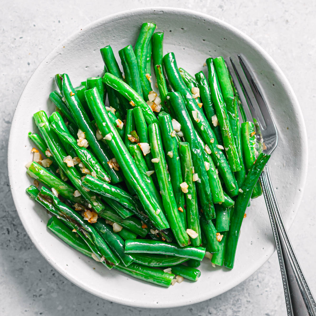 Sautéed garlic green beans served on a ceramic plate.