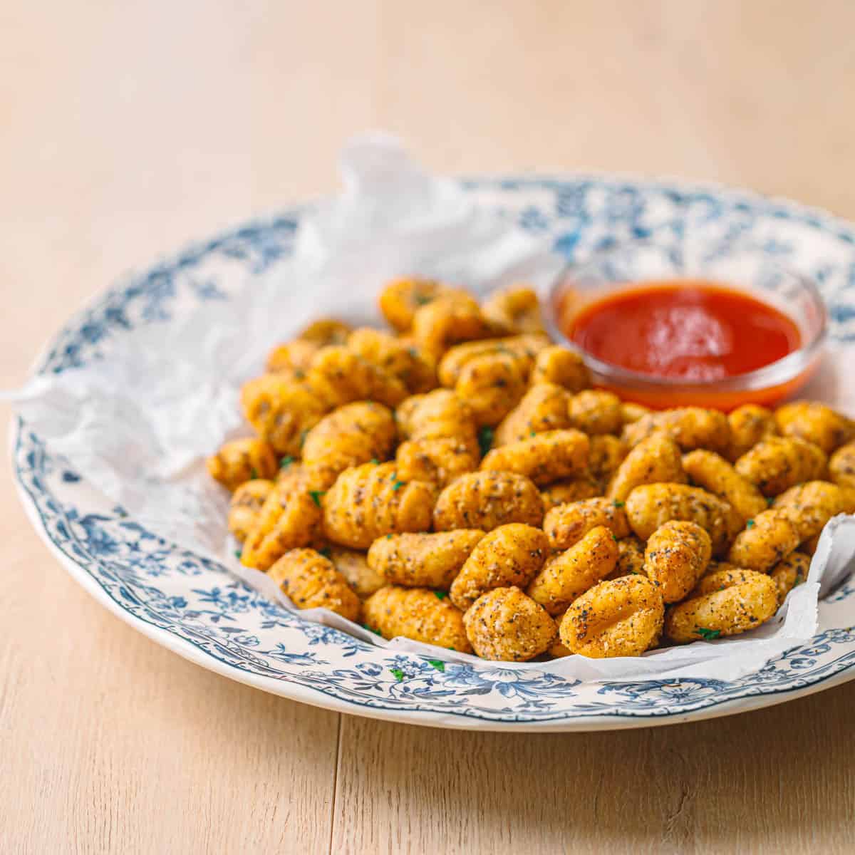 Air fried gnocchi in a ceramic bowl with marinara dipping sauce.