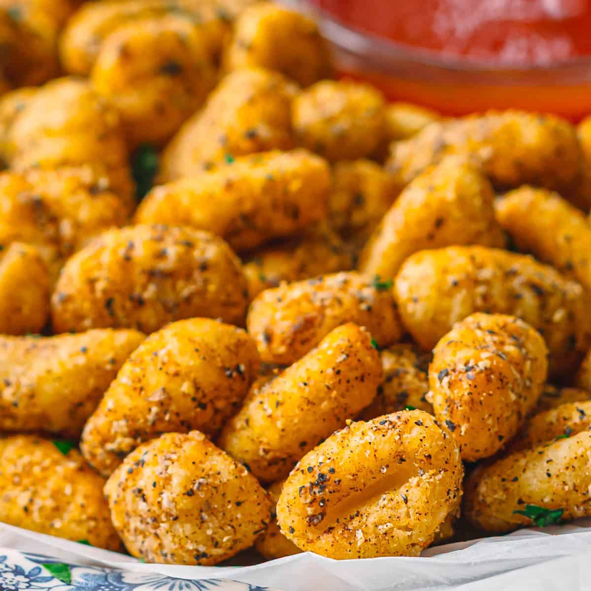 Crispy air fryer gnocchi in a ceramic bowl with marinara sauce.